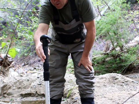 Environmental technician testing water quality in a stream